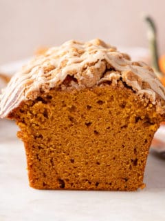 Cross-section view of a loaf of streusel-topped pumpkin bread with maple glaze.
