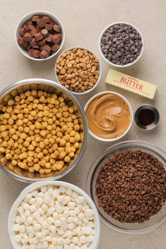 Ingredients for peanut butter cup rice krispie treats arranged on a beige countertop.