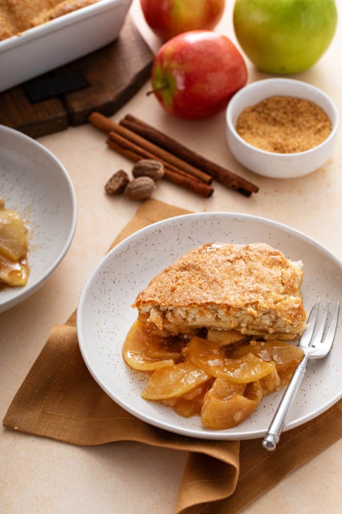 Serving of apple cobbler next to a fork in a shallow bowl.