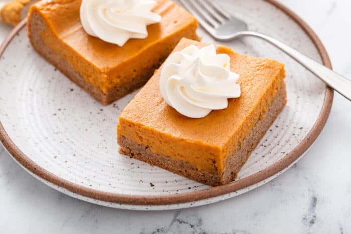 Two slices of pumpkin gooey butter cake on a plate.