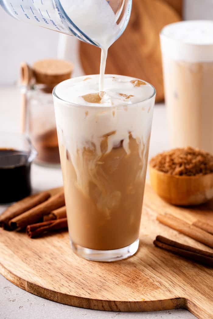 Glass of iced coffee being topped with vanilla sweet cream cold foam.