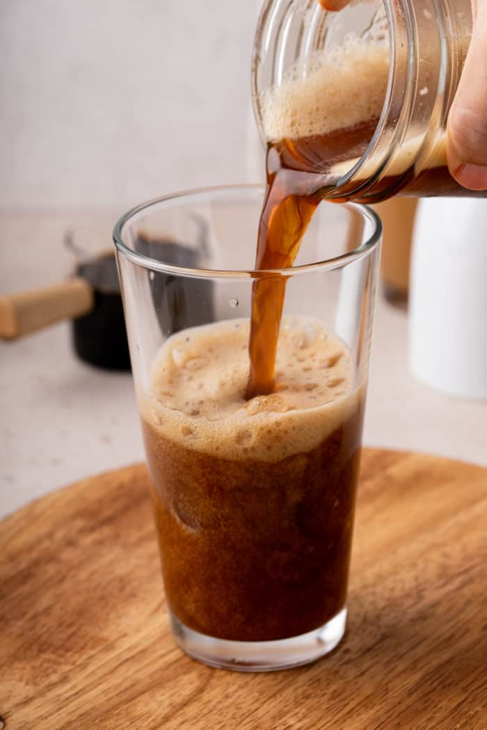 Frothy, iced shaken espresso being poured into a glass.