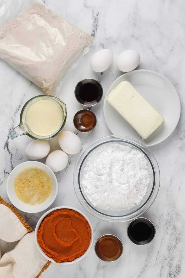 Ingredients for pumpkin gooey butter cake arranged on a marble countertop.