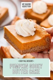 Hand holding up a slice of pumpkin gooey butter cake topped with a dollop of whipped cream. Text overlay includes recipe name.