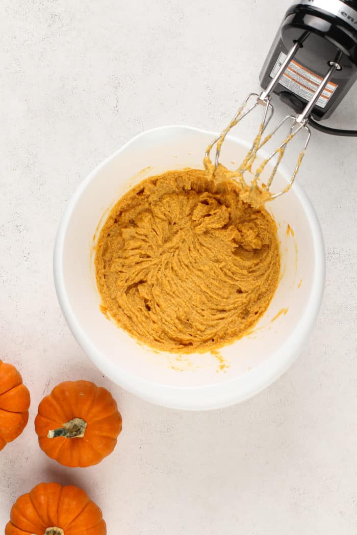 Wet ingredients for pumpkin snickerdoodles beaten together in a white mixing bowl.