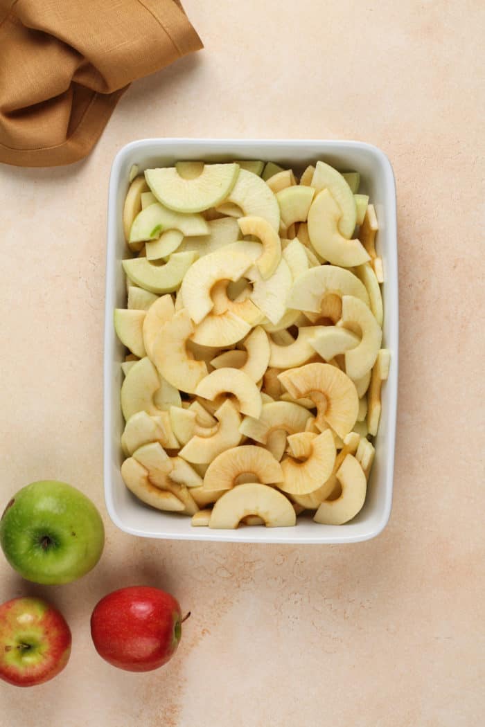 Sliced apples in a white baking dish.
