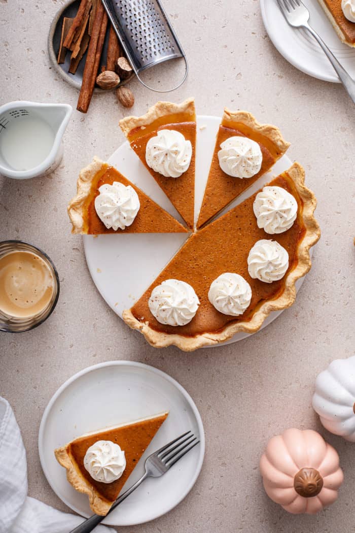 overhead view of a sliced pumpkin cream cheese pie garnished with whipped cream.