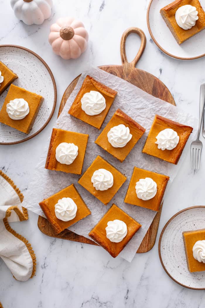 Overhead view of slices of pumpkin gooey butter cake arranged on a piece of parchment paper.