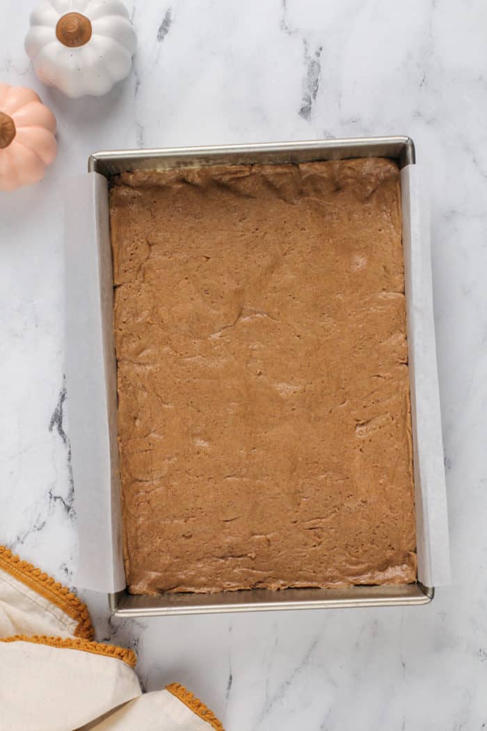 Spice cake crust pressed into a parchment-lined cake pan.