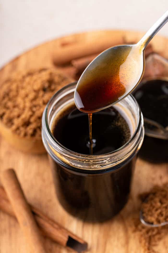 Spoon drizzling brown sugar syrup back into a jar.