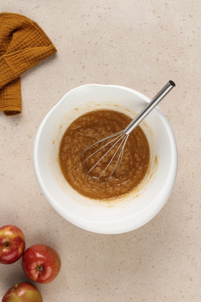 Vegetable oil and sugar whisked together in a white mixing bowl.