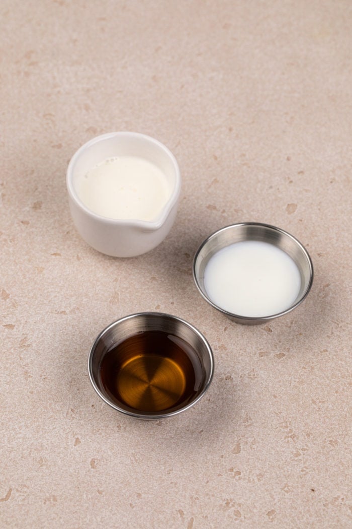 Ingredients for vanilla sweet cream cold foam arranged on a beige countertop.