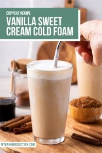 Hand stirring a straw in a glass of iced coffee topped with vanilla sweet cream cold foam. Text overlay includes recipe name.