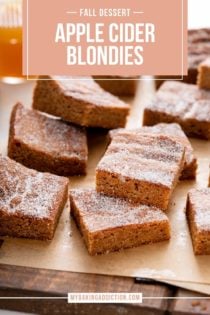 Apple cider blondies scattered on a piece of brown parchment paper. Text overlay includes recipe name.