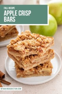 Three apple crisp bars stacked on a white plate. The top bar has a bite taken from the corner. Text overlay includes recipe name.