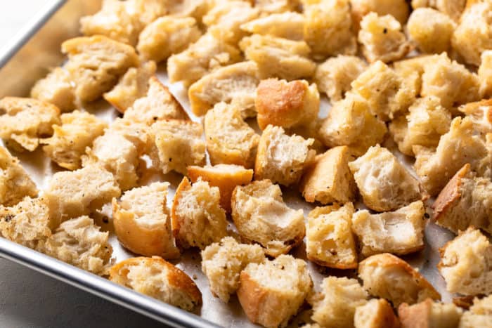 Baked homemade croutons on a rimmed baking sheet.