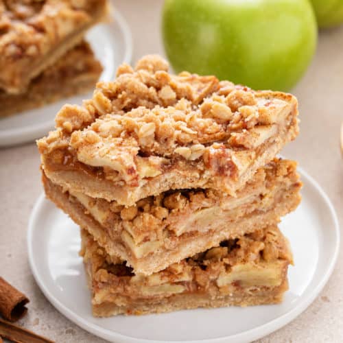 Bite from an apple crisp bar on the top of a stack of bars.