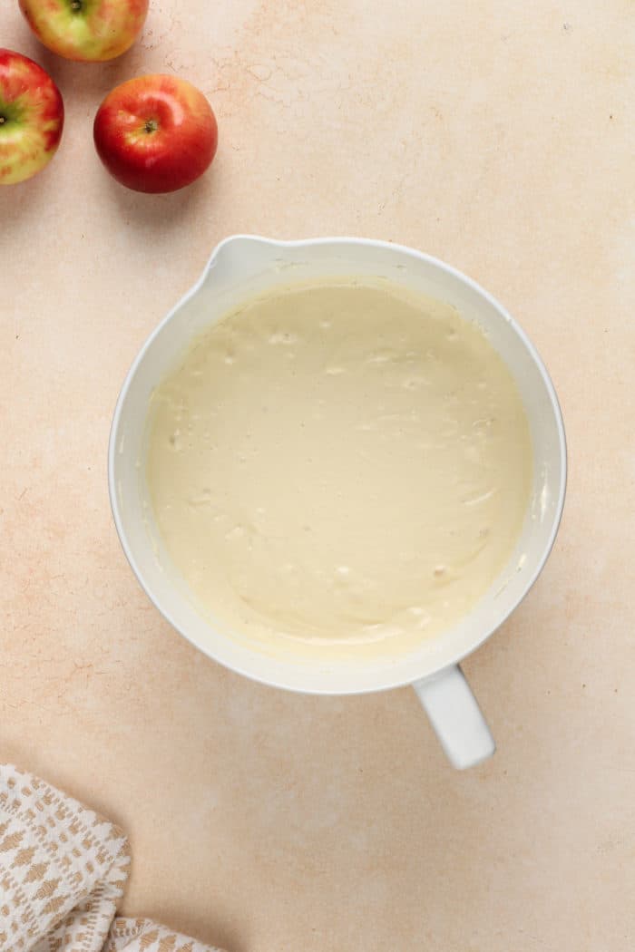 Eggs added to cream cheese in a white mixing bowl.