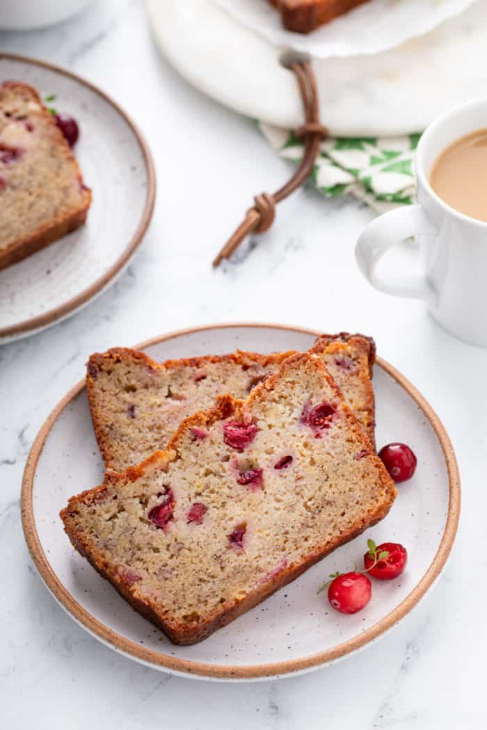 Two slices of cranberry banana bread on a speckled plate.