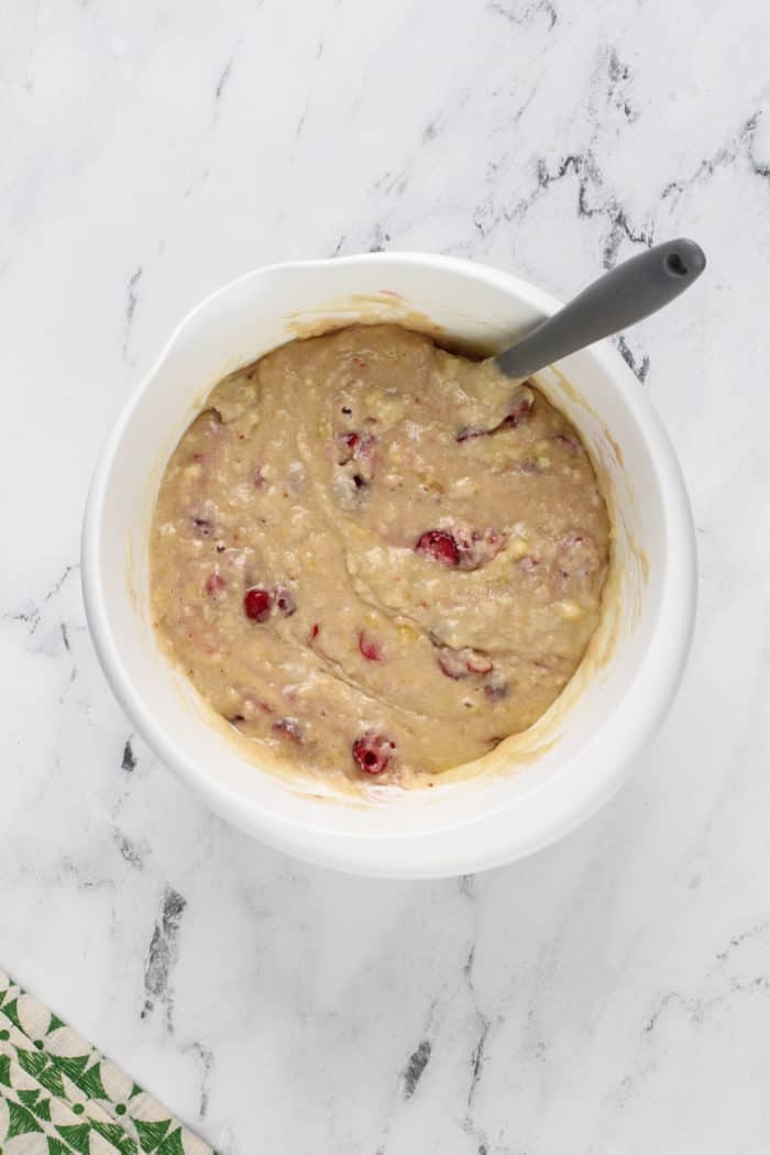 Batter for cranberry banana bread in a white mixing bowl.