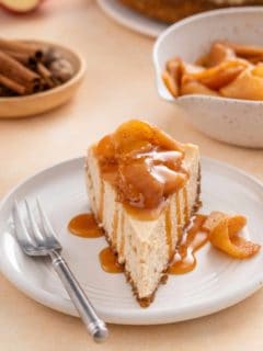 Front view of a slice of caramel apple cheesecake on a plate next to a fork.