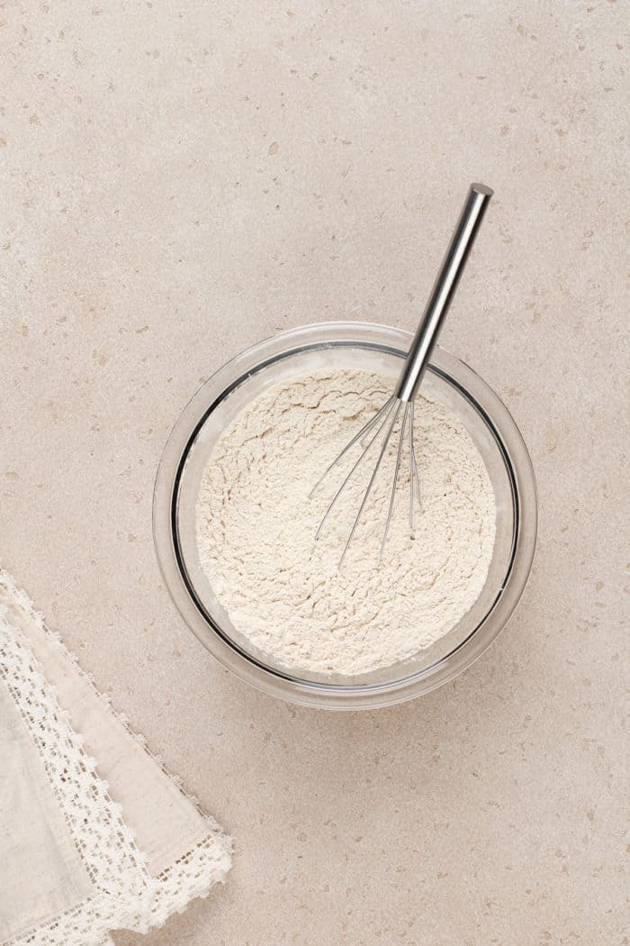 Dry ingredients being whisked together in a glass mixing bowl.