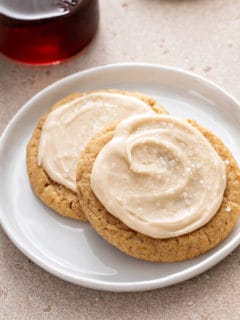 Two frosted maple cookies on a white plate.