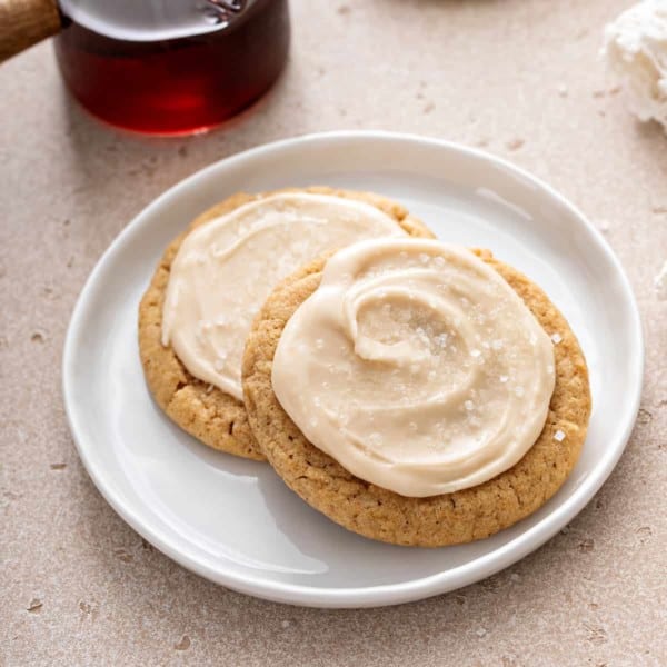 Two frosted maple cookies on a white plate.