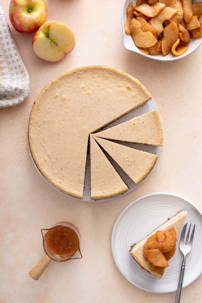 Overhead view of sliced caramel apple cheesecake next to a plate of assembled and garnished caramel apple cheesecake.