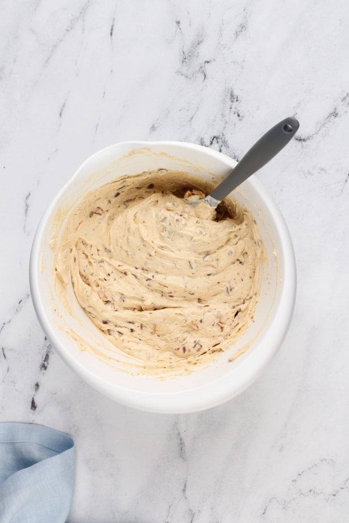 Snickers dip stirred together in a white mixing bowl.