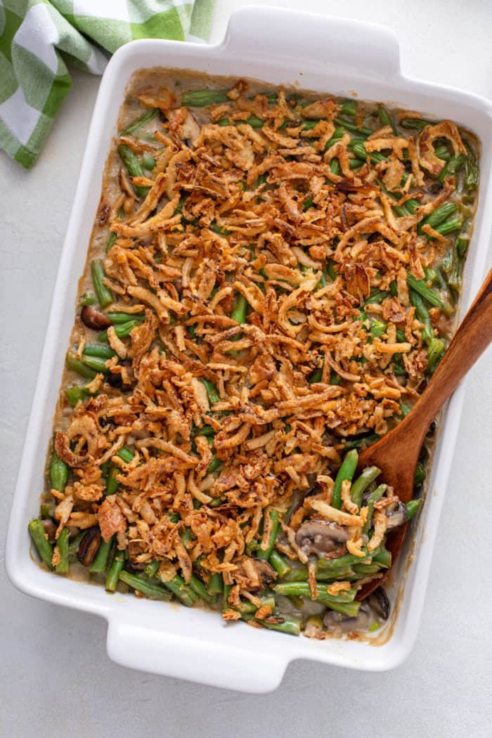 Overhead view of baked fresh green bean casserole with a wooden spoon in the dish.