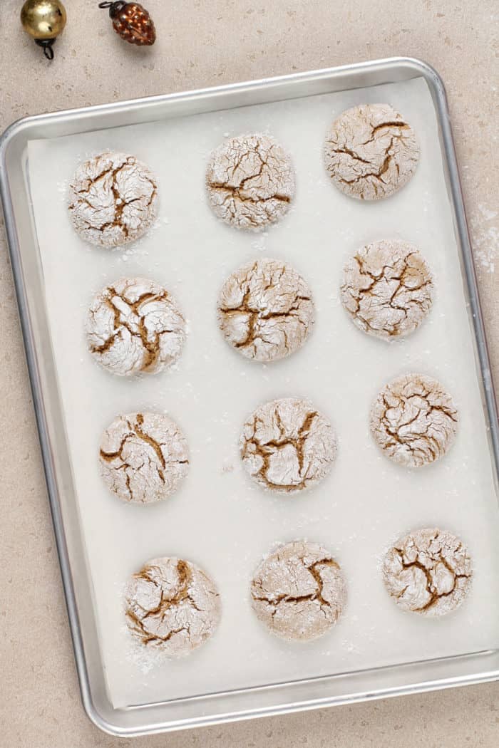 Baked gingerbread crinkle cookies on a parchment-lined baking sheet.