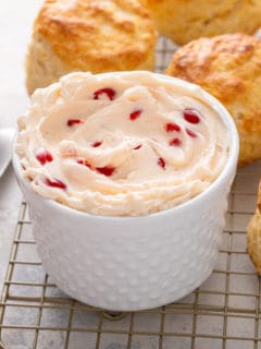 White bowl filled with whipped cherry butter set on a wire rack of biscuits.