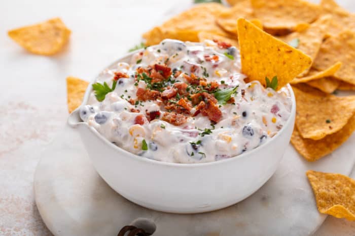 Bowl of fiesta ranch dip with a tortilla chip in it.