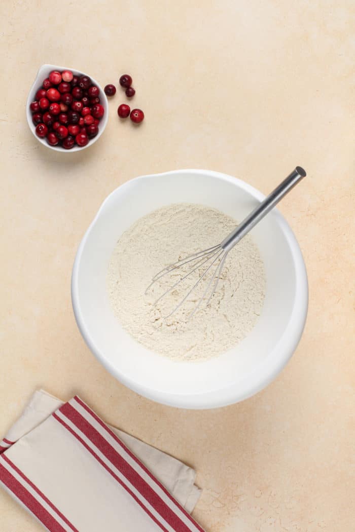 Dry ingredients for muffins being whisked in a white mixign bowl.