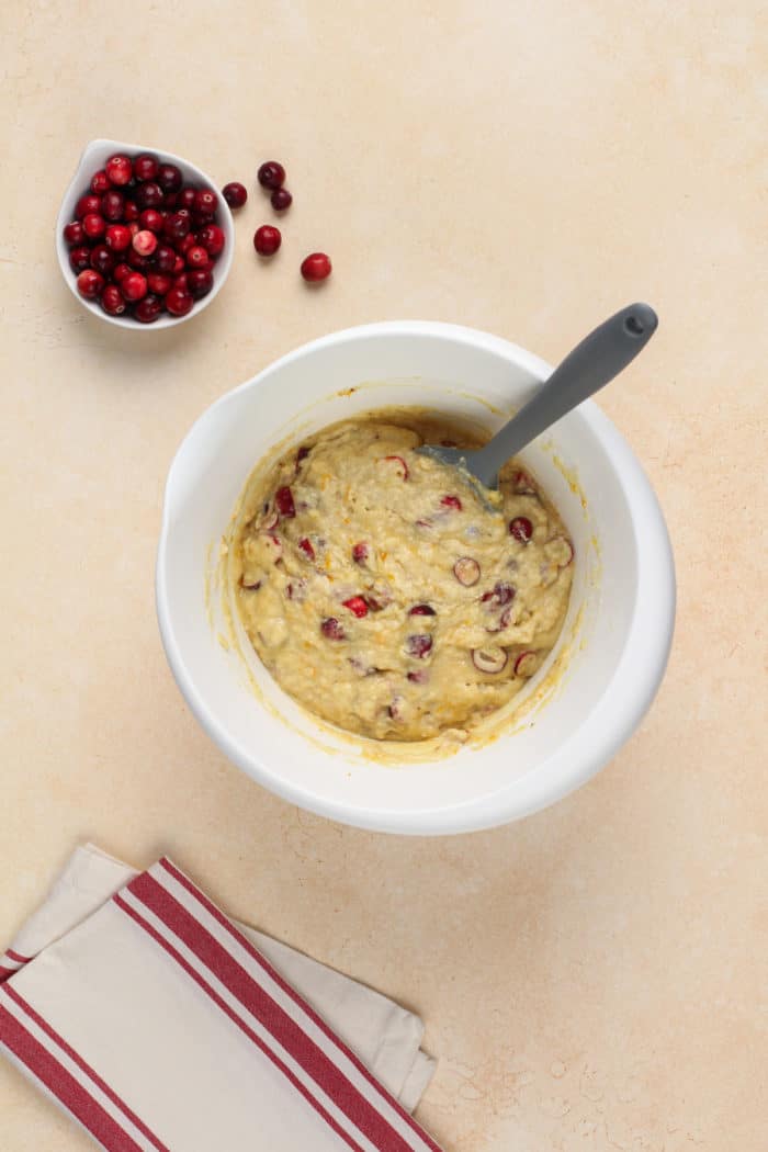 White mixing bowl filled with cranberry orange muffin batter.