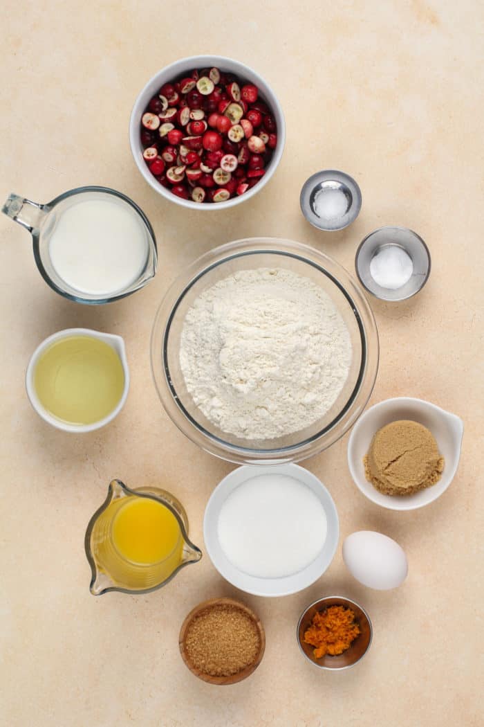 Ingredients for cranberry orange muffins arranged on a beige countertop.