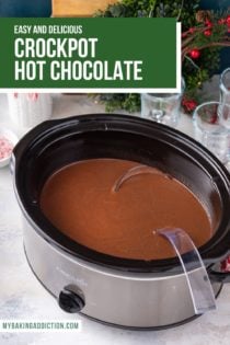 Large slow cooker filled with hot chocolate on a countertop, with glasses and toppings in the background. Text overlay includes recipe name.
