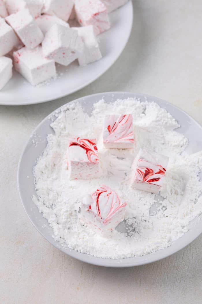 Cut peppermint marshmallows being dredged in powdered sugar and cornstarch.