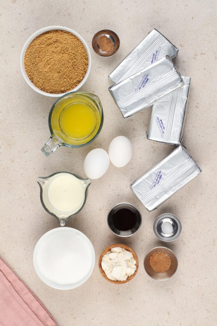 Ingredients for eggnog cheesecake arranged on a beige countertop.