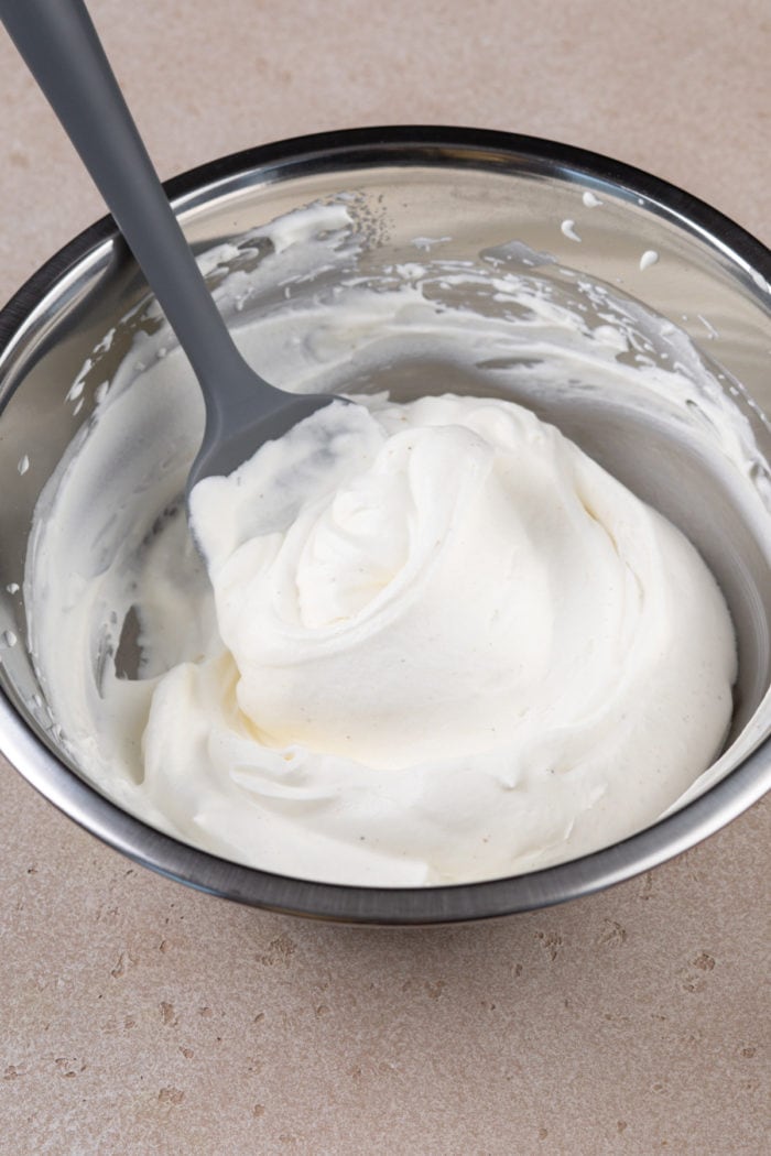 Eggnog whipped cream in a metal mixing bowl.