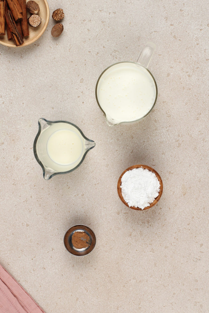 Ingredients for eggnog whipped cream on a beige countertop.