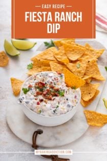 White bowl of fiesta ranch dip on a marble board next to Doritos tortilla chips. Text overlay includes recipe name.