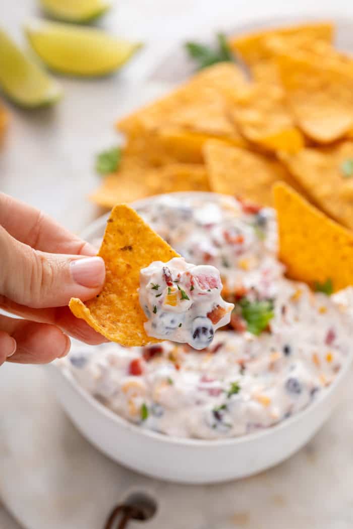 Hand holding up a chip with fiesta ranch dip on it.
