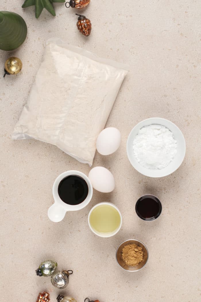 Ingredients for gingerbread crinkle cookies arranged on a beige countertop.