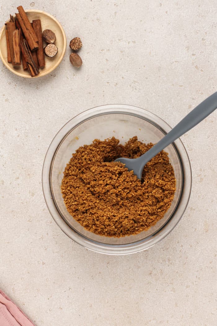 Gingersnap cookie crumbs and butter mixed in a glass bowl.