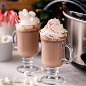 Two glass mugs filled with crockpot hot chocolate.