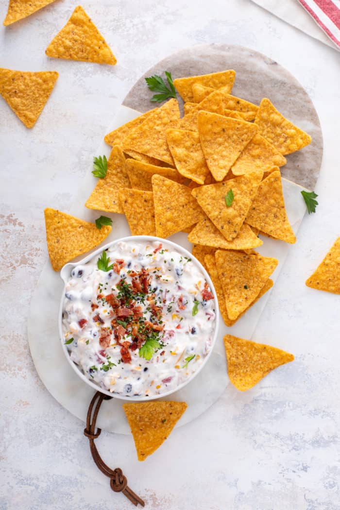 Overhead view of a bowl of fiesta ranch dip next to Doritos tortilla chips on a marble board.