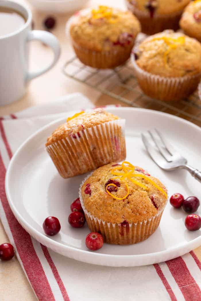 Two cranberry orange muffins on a white plate.