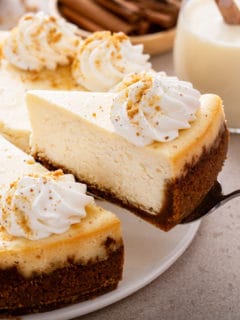 Serving a slice of eggnog cheesecake topped with whipped cream.